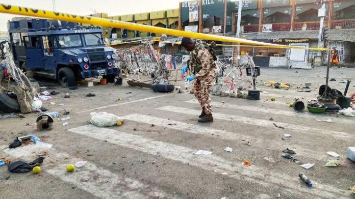 Police officers on Tuesday morning at the scene of the previous night’s explosion at a market in Maiduguri. Photograph: Jossy Ola/AP Police officers on Tuesday morning at the scene of the previous night’s explosion at a market in Maiduguri. Photograph: Jossy Ola/AP